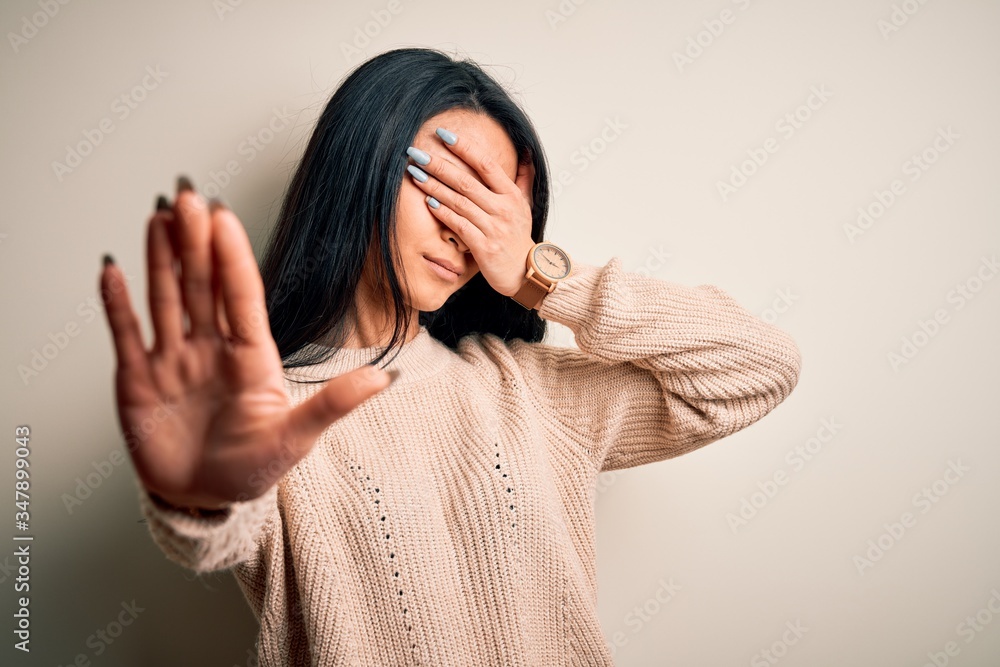 Young beautiful chinese woman wearing casual sweater over isolated white background covering eyes with hands and doing stop gesture with sad and fear expression. Embarrassed and negative concept. Young beautiful chinese woman wearing casual sweater over isolated white background covering eyes with hands and doing stop gesture with sad and fear expression. Embarrassed and negative concept.