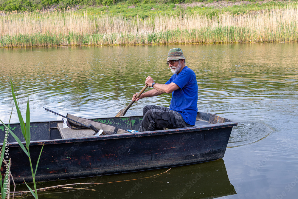 Senior fisherman in a boat at Danube-Tisa-Danube channel near Novi Sad, Serbia.