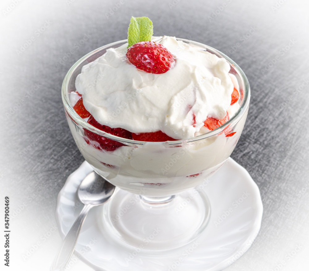 Strawberries with whipped cream in a glass bowl on dark background Strawberries with whipped cream in a glass bowl on dark background