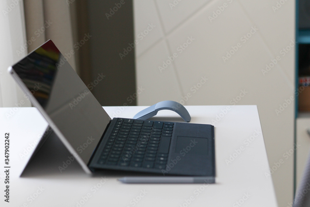 Office workplace with modern laptop on white table and white office desk, office chair. Stay at home, work from home. Grey, white, black. Online work, education, shopping, marketing. Pencil. Office workplace with modern laptop on white table and white office desk, office chair. Stay at home, work from home. Grey, white, black. Online work, education, shopping, marketing. Pencil.