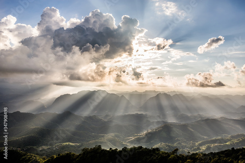 Golden light rays from clouds shining down to mountains. Sun rays over valley. Sun rays over hill. Beam of light from clouds on the mountains. Heaven in nature. Mon Pui Mok, Mae Moei, Tak, Thailand.