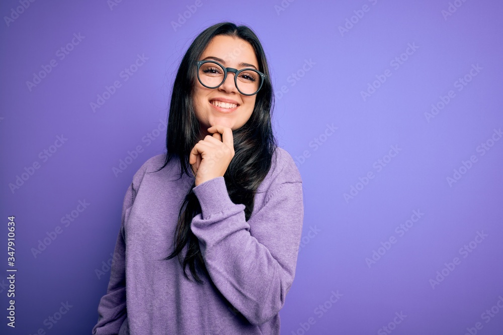 Young brunette woman wearing glasses over purple isolated background looking confident at the camera with smile with crossed arms and hand raised on chin. Thinking positive.