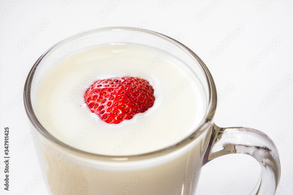 red fresh ripe sweet strawberries floating in cow's milk poured in a clear glass glass on a white background Breakfast place for text red fresh ripe sweet strawberries floating in cow's milk poured in a clear glass glass on a white background Breakfast place for text