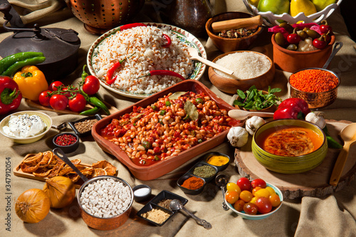 cooked and uncooked haricot beans, served with traditional cooked rice and Traditional red lentil soup. Table garnished with legumes, vegetables and seasonings. Rich cuisine, delicious food.