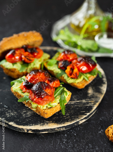 Close up of vegan and healthy sandwiches with avocado, roasted tomatoes and arugula