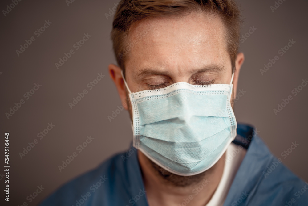 Male doctor feeling exhausted after long shift treating coronavirus infected patients at hospital Male doctor feeling exhausted after long shift treating coronavirus infected patients at hospital