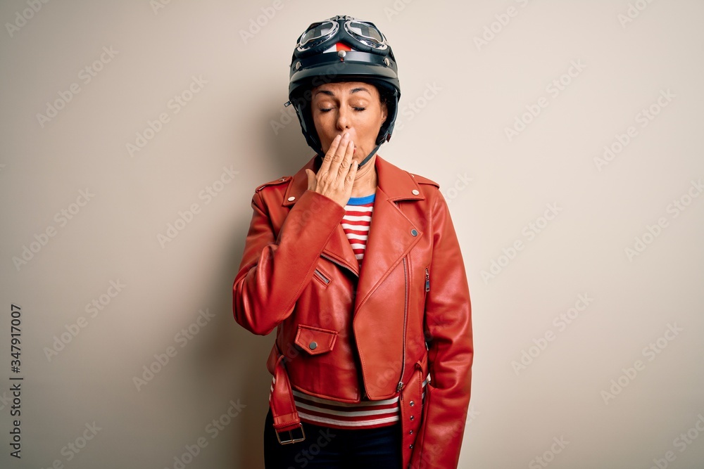 Middle age motorcyclist woman wearing motorcycle helmet and jacket over white background bored yawning tired covering mouth with hand. Restless and sleepiness. Middle age motorcyclist woman wearing motorcycle helmet and jacket over white background bored yawning tired covering mouth with hand. Restless and sleepiness.