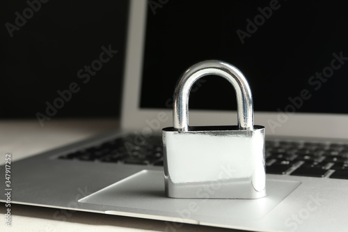 Metal lock and laptop on table, closeup. Protection from cyber attack