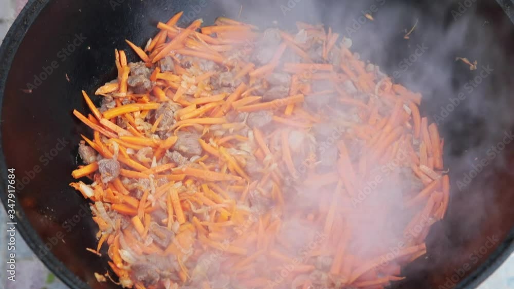 Preparation of national uzbek dish pilaf, pilaw, plov, carrot with meat
