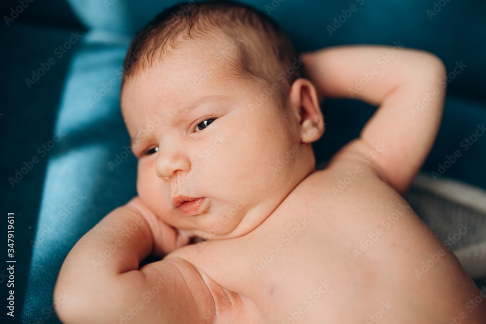 newborn baby lies on a sofa and looks newborn baby lies on a sofa and looks