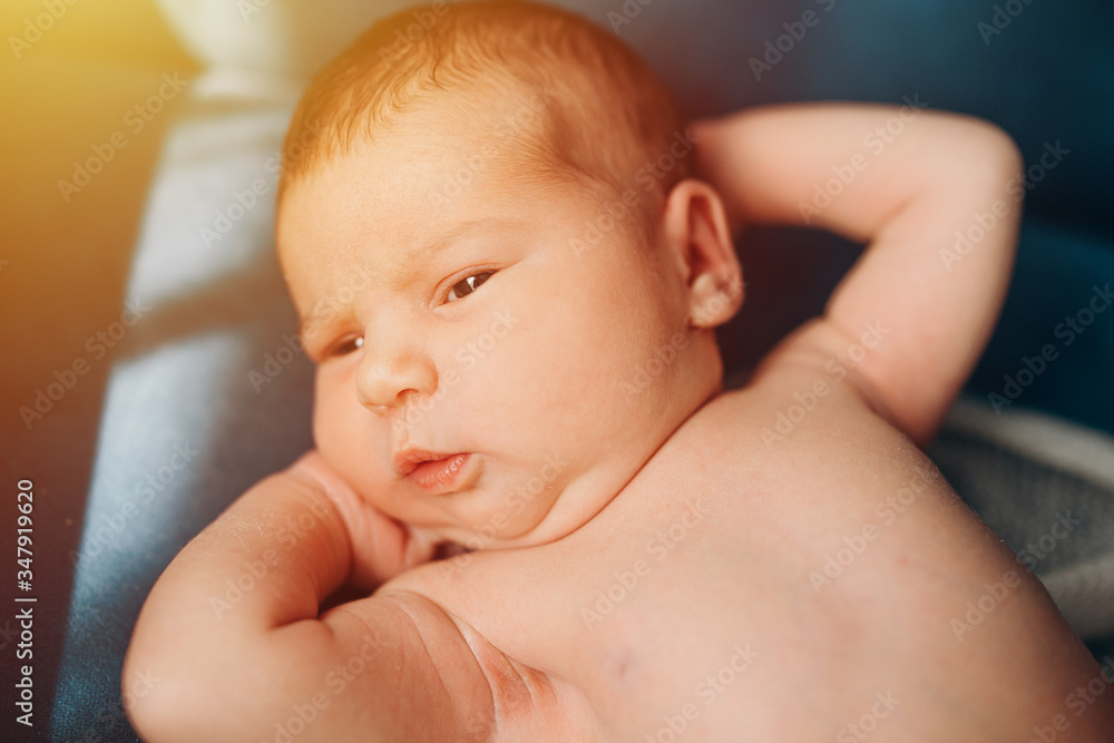newborn baby lies on a sofa and looks newborn baby lies on a sofa and looks