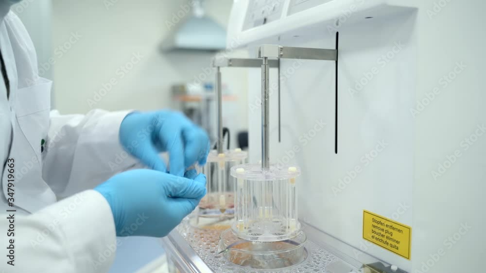 Scientist chemist testing new drugs during working day in pharmaceutical laboratory spbas. Man puts pills in equipment compartment and starts process while standing in interior of modern plant Scientist chemist testing new drugs during working day in pharmaceutical laboratory spbas. Man puts pills in equipment compartment and starts process while standing in interior of modern plant