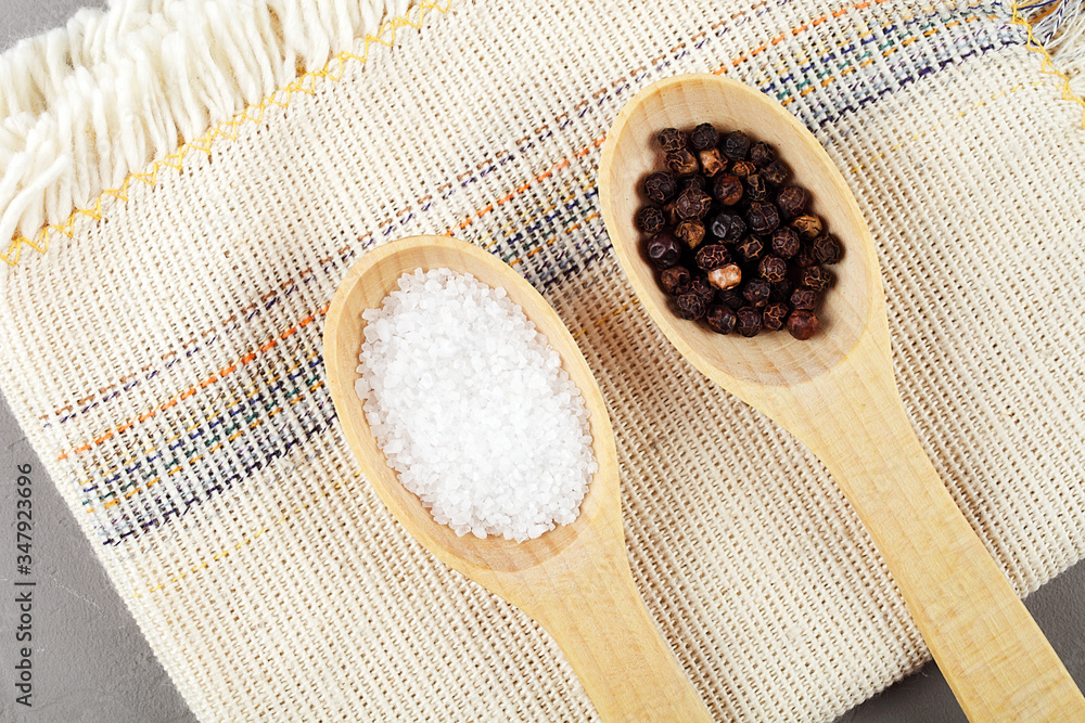Wooden spoons on a linen napkin with pepper and sea salt, top view Wooden spoons on a linen napkin with pepper and sea salt, top view