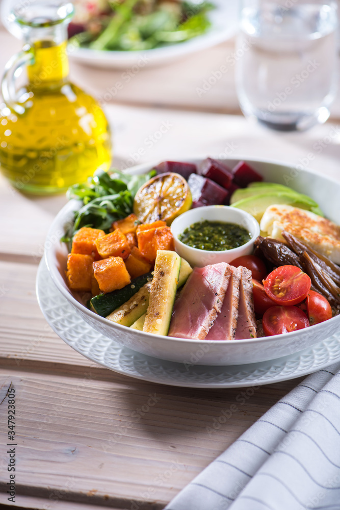 Bowl with vegetables and tuna fish on a table with olive oil at a restaurant. Salad ingredients with fresh vegetables and tuna. Bowl with vegetables and tuna fish on a table with olive oil at a restaurant. Salad ingredients with fresh vegetables and tuna.