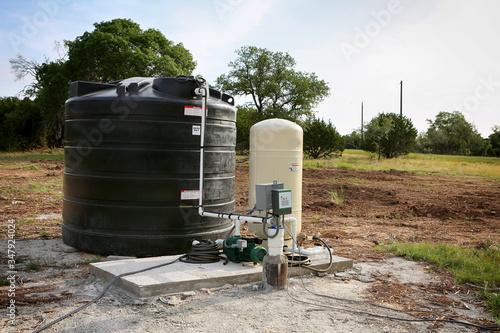 Deep water well set up, country side construction. Drilled draw well with pressure switch and storage tank.