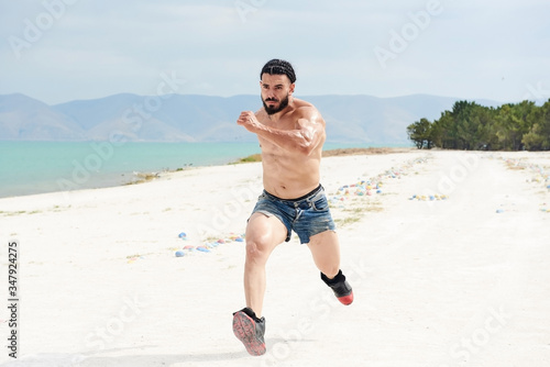 muscular young man running on the beach, muscular  athlete running on the beach