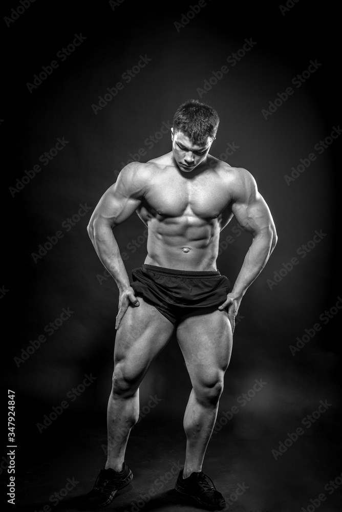 Fototapeta premium Sexy young athlete posing on a black background in the Studio. Fitness, bodybuilding, black and white