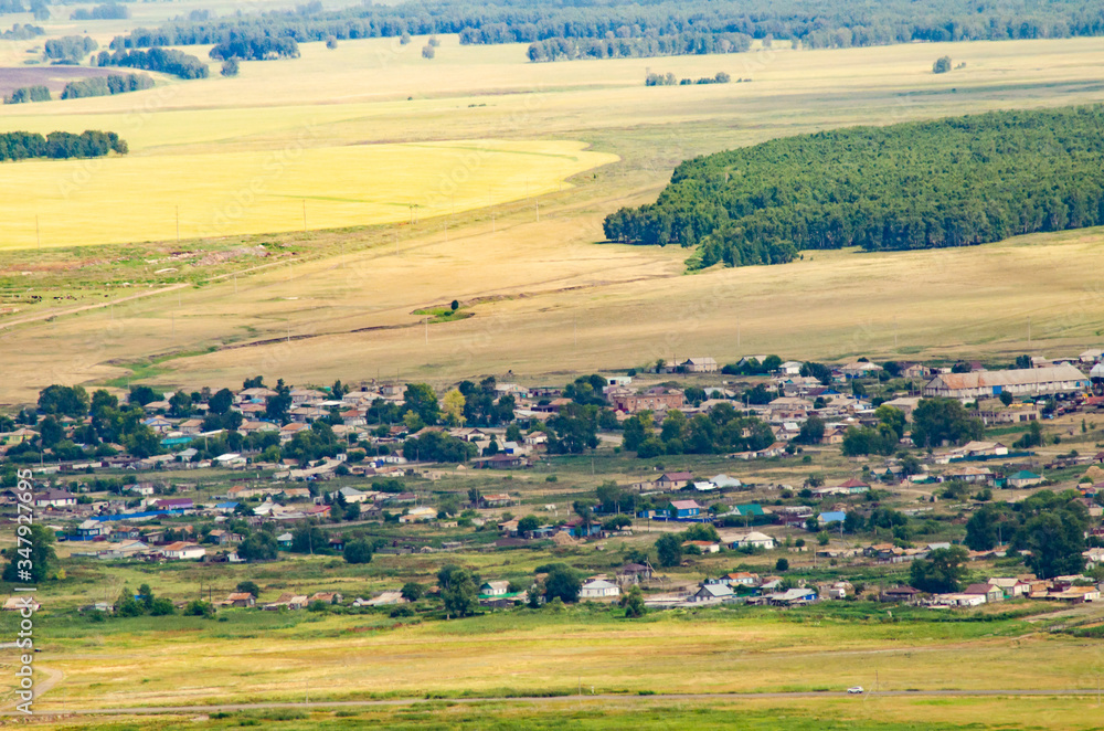 Fototapeta premium village in the mountains aerial view among fields and mountains and clouds by the lake