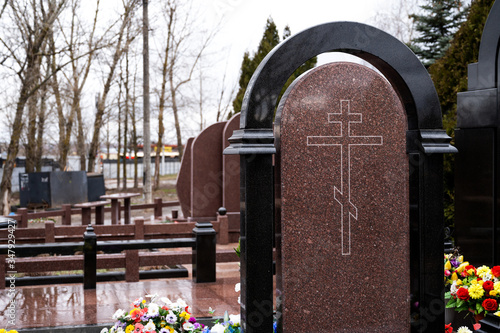 marble tombstone with fresh flowers on a grave in a cemetery. the funeral of dear people.