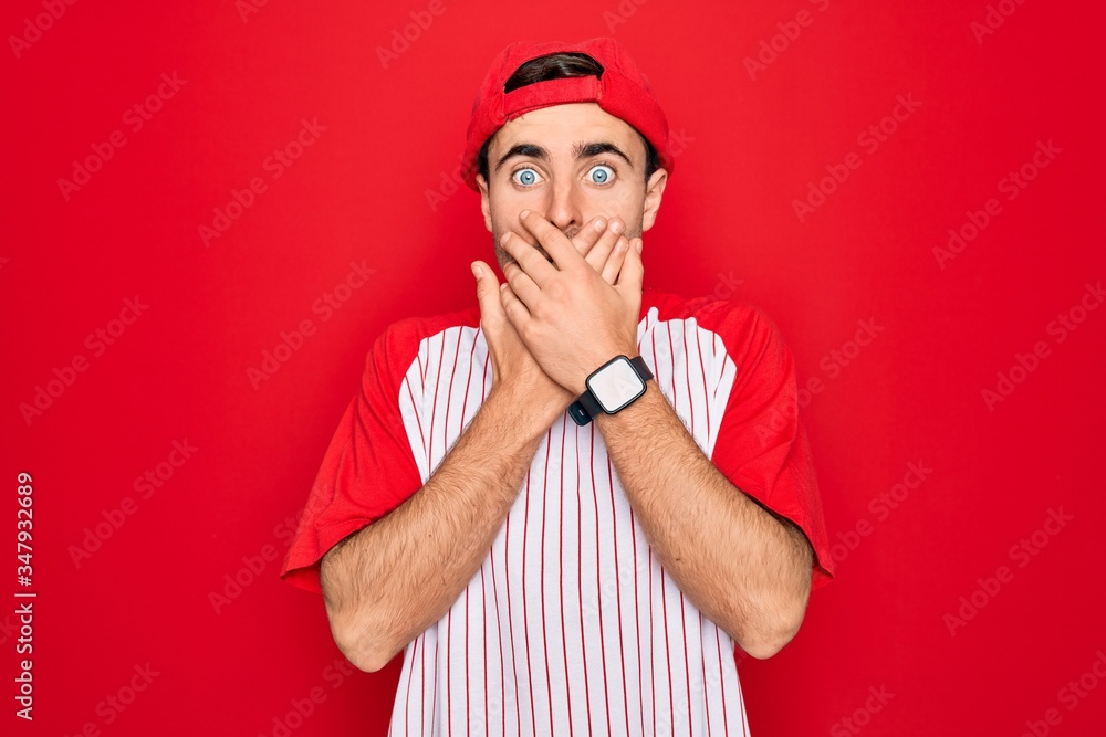 Young handsome sporty man with blue eyes wearing striped baseball t-shirt and cap shocked covering mouth with hands for mistake. Secret concept. Young handsome sporty man with blue eyes wearing striped baseball t-shirt and cap shocked covering mouth with hands for mistake. Secret concept.