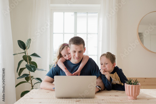 parent working from home with kids climbing on him photo