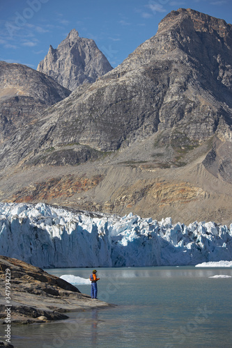 man standing at the water's edge of a fjord in Greenland photo