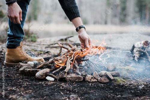 man putting logs on a handmade campfire outdoors in Sweden photo