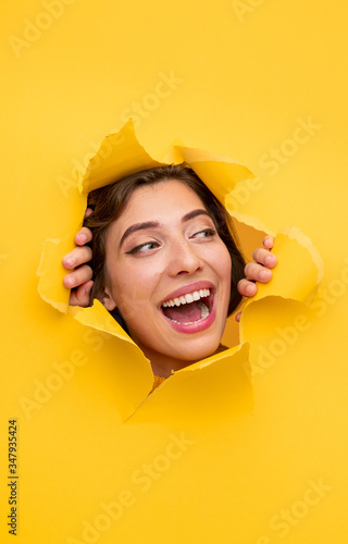 Happy woman tearing hole in yellow paper © kegfire