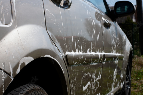 the car is covered in soapy white foam. car wash.