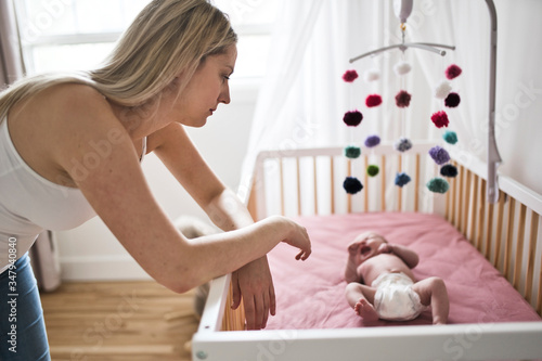 mother suffering from postnatal depression near crib with cute baby at home photo