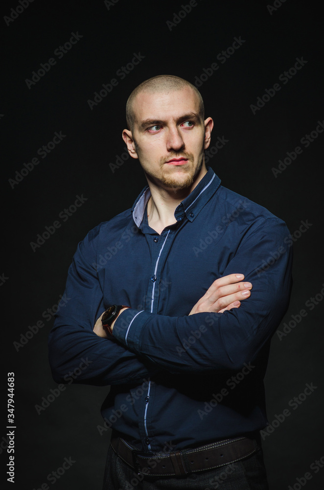 A stylish, bald young man stands on a dark background in the category. Business, Finance A stylish, bald young man stands on a dark background in the category. Business, Finance