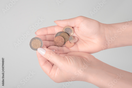 woman considers Euro coins. Only hands and money are visible.