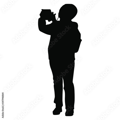 Silhouette of standing person in sportive tourist clothes taking photograph.