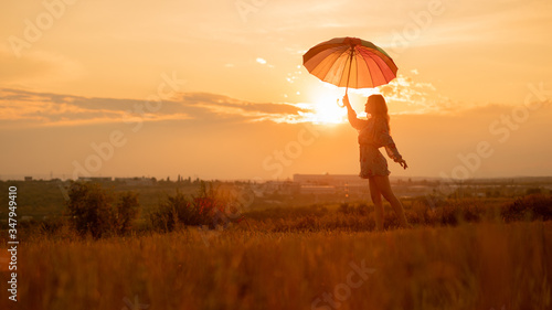 Inspiring female with umbrella against sunset sky