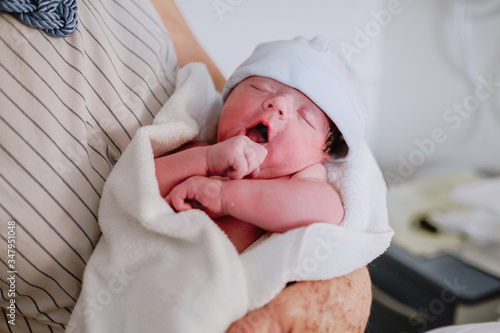 Happy mature female greeting newborn grandchild in hospital ward photo