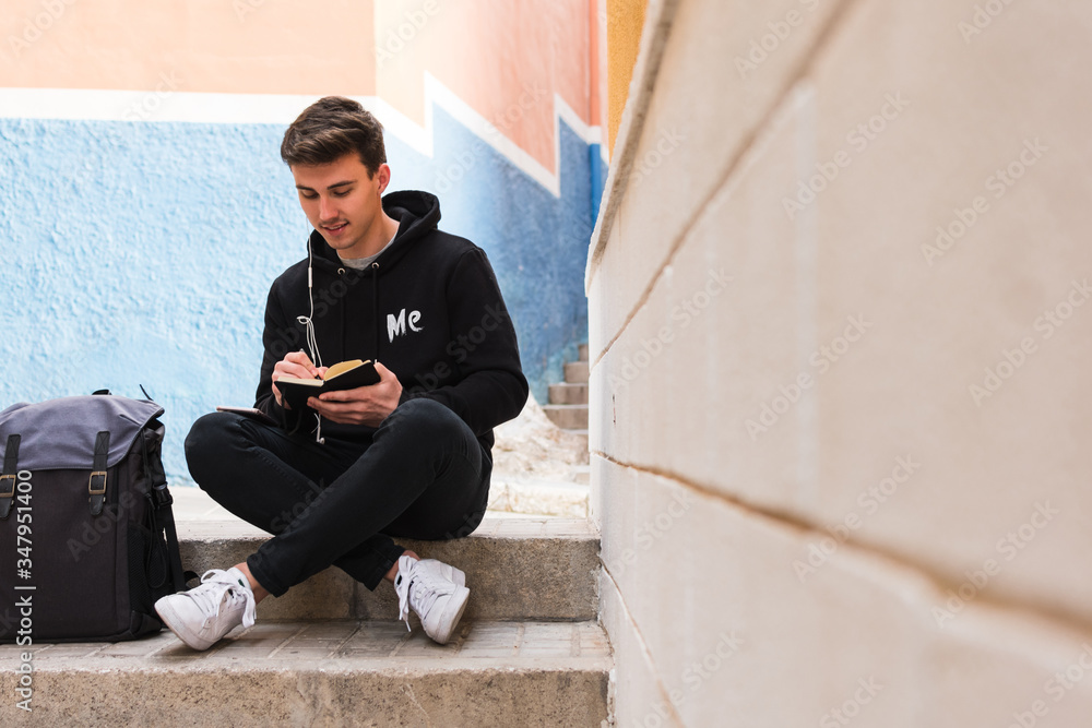 Male student making notes on street Male student making notes on street
