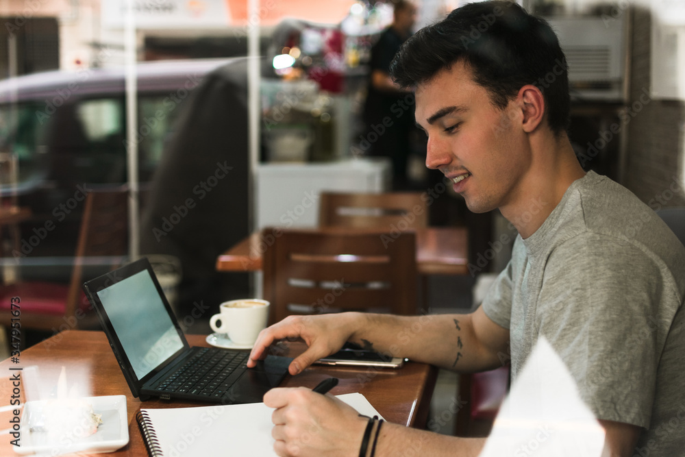 Freelancer sitting at cafe table and browsing laptop Freelancer sitting at cafe table and browsing laptop