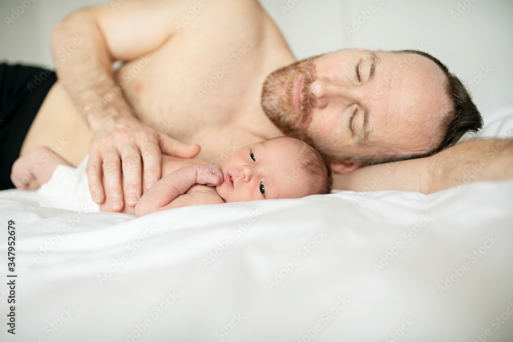 A father with a newborn baby in bed A father with a newborn baby in bed