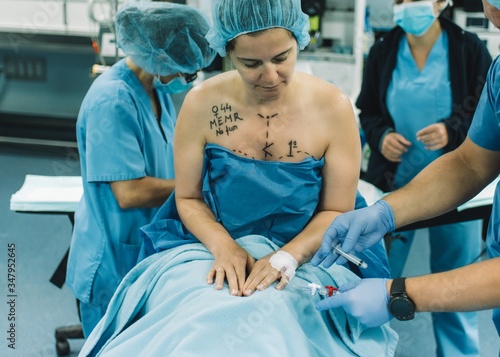 Blurred surgeon using photo camera to shoot breast of female patient before performing mammoplasty in modern hospital photo