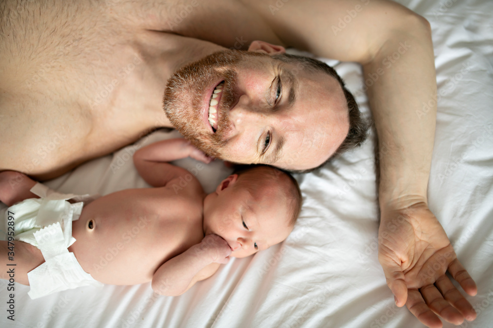 top view of A father with a newborn baby in bed top view of A father with a newborn baby in bed