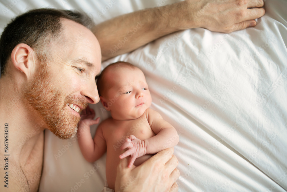 A father with a newborn baby in bed A father with a newborn baby in bed