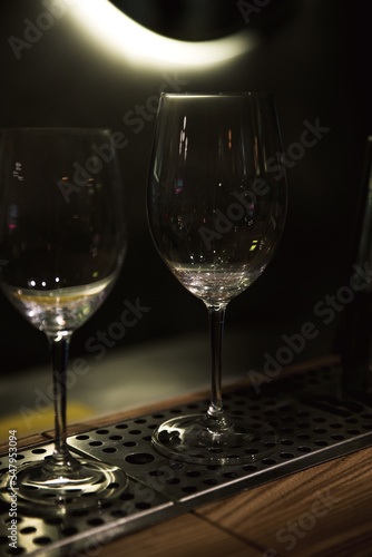 Two empty wine glasses for cocktails on a dark neon background. two empty glasses nearby. bartender 