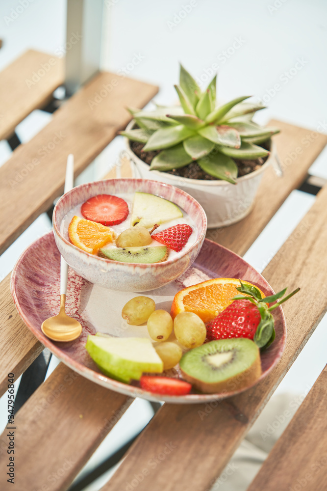 From above of tasty healthy breakfast with yogurt and assorted colorful fresh fruits served on wooden table From above of tasty healthy breakfast with yogurt and assorted colorful fresh fruits served on wooden table