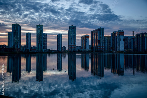 Stunning sunset view with beautiful sky above the high-rise buildings and reflection in the lake. Residential complex Sofia St. Petersburg.