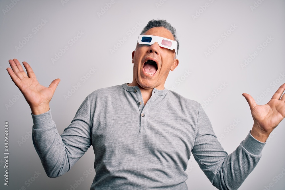 Middle age handsome grey-haired man using 3d glasses over isolated white background crazy and mad shouting and yelling with aggressive expression and arms raised. Frustration concept. Middle age handsome grey-haired man using 3d glasses over isolated white background crazy and mad shouting and yelling with aggressive expression and arms raised. Frustration concept.