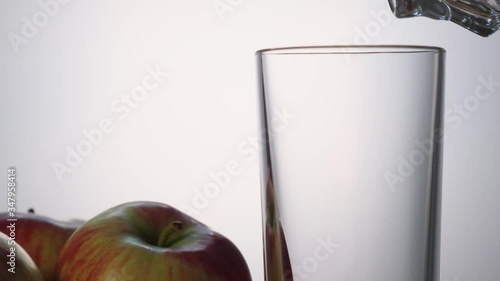 Apple juice is poured into a transparent glass close-up slow motion