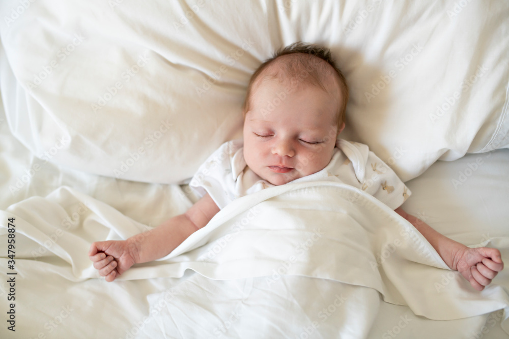 A Sweet newborn baby girl sleeping in white bed A Sweet newborn baby girl sleeping in white bed