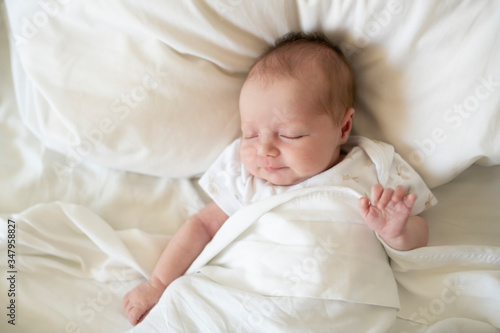 A Sweet newborn baby girl sleeping in white bed