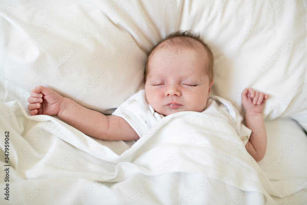 A Sweet newborn baby girl sleeping in white bed A Sweet newborn baby girl sleeping in white bed