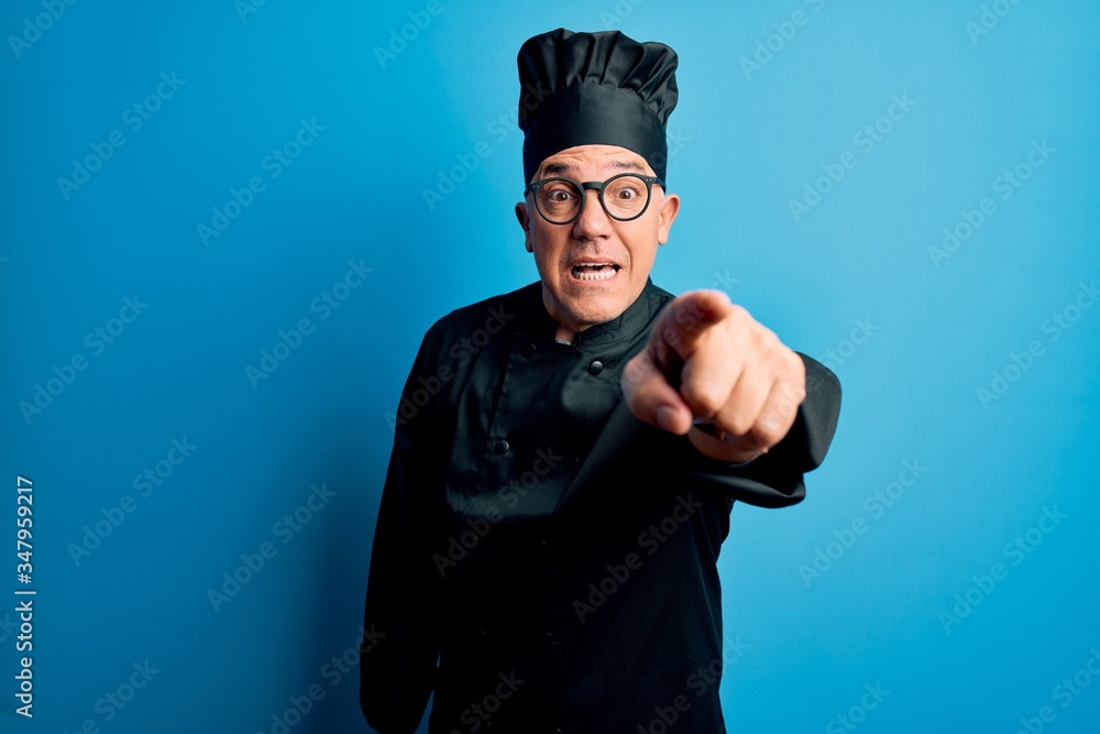 Middle age handsome grey-haired chef man wearing cooker uniform and hat pointing displeased and frustrated to the camera, angry and furious with you Middle age handsome grey-haired chef man wearing cooker uniform and hat pointing displeased and frustrated to the camera, angry and furious with you
